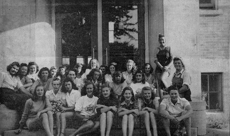 The Forest Farmerettes sitting on stairs outside the high school.