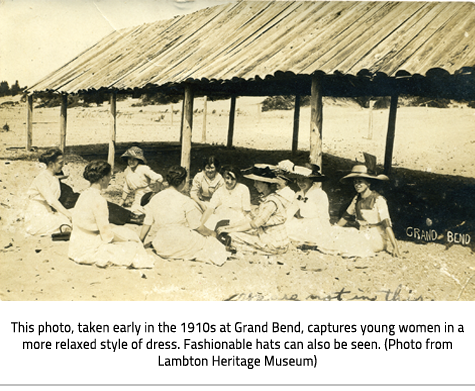 (A group of women sitting on Grand Bend Beach next to a wooden pavilion. They all wear long dresses, have their hair in up-dos and many wear large hats  Image Caption: "This photo, taken early in the 1910s at Grand Bend, captures young women in a more relaxed style of dress. Fashionable hats can also be seen. (Photo from Lambton Heritage Museum)"), link.