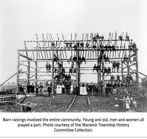 (peopel in and around the frame of a barn. Some people sit on beams. Image Caption: "Barn raisings involved the entire community. Young and old, men and women all played a part. Photo courtesy of the Warwick Township History Committee Collection."), link.
