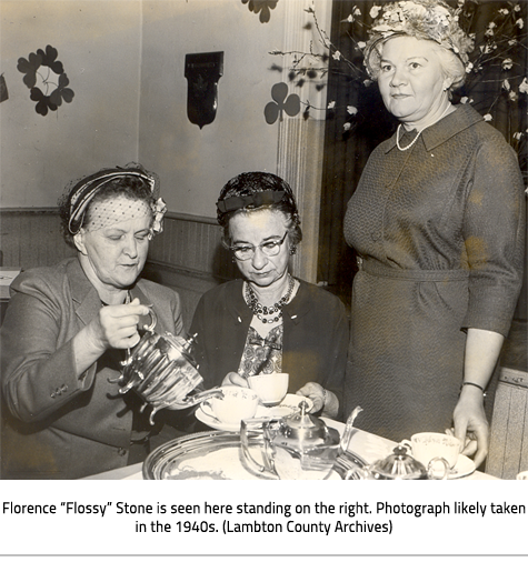(Two women sitting at a table serving tea. One woman stands beside them. Image caption: "Florence “Flossy” Stone is seen here standing on the right. Photograph likely taken in the 1940s. (Lambton County Archives)"), link.