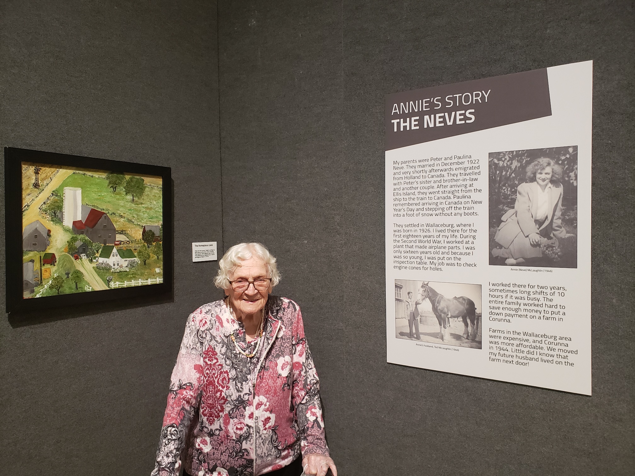 Lady standing with a walker next to a painting.