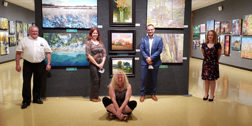 Five people standing around hung paintings at the Lambton Heritage Museum