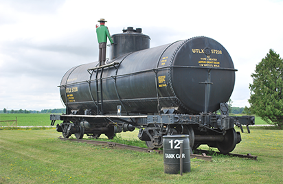 Large, black Procor Limited tank car outside with a barrel, link.