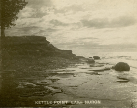 (A stony beach with large spherical stones rising from the water not far from the beach. The text at the bottom reads: "Kettle Point Lake Huron"), link.
