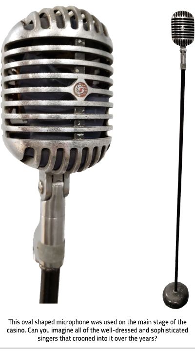 (Oval shaped microphone with long oval shaped holes rests on a tall black stand with a circular base. On the left is the close up of just the microphone, on the left is full sized image with the stand. Image Caption: "This oval shaped microphone was used on the main stage of the casino. Can you imagine all of the well-dressed and sophisticated singers that crooned into it over the years? " ), link.