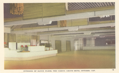 (A postcard showing the casino's dance floor. The floor goes from deep orange and yellow. The ceiling is purple, and off to the left side there is a white stage. The text below the image reads: "Interior of Dance Floor, The Casino, Grand Bend, Ontario, Can.  12 "), link.