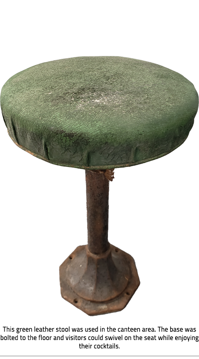 (Stool with cracked and flaking green cushion and rusted base. In the base there are holes to screw it into the floor. Image Caption: "This green leather stool was used in the canteen area. The base was bolted to the floor and visitors could swivel on the seat while enjoying their cocktails."), link.