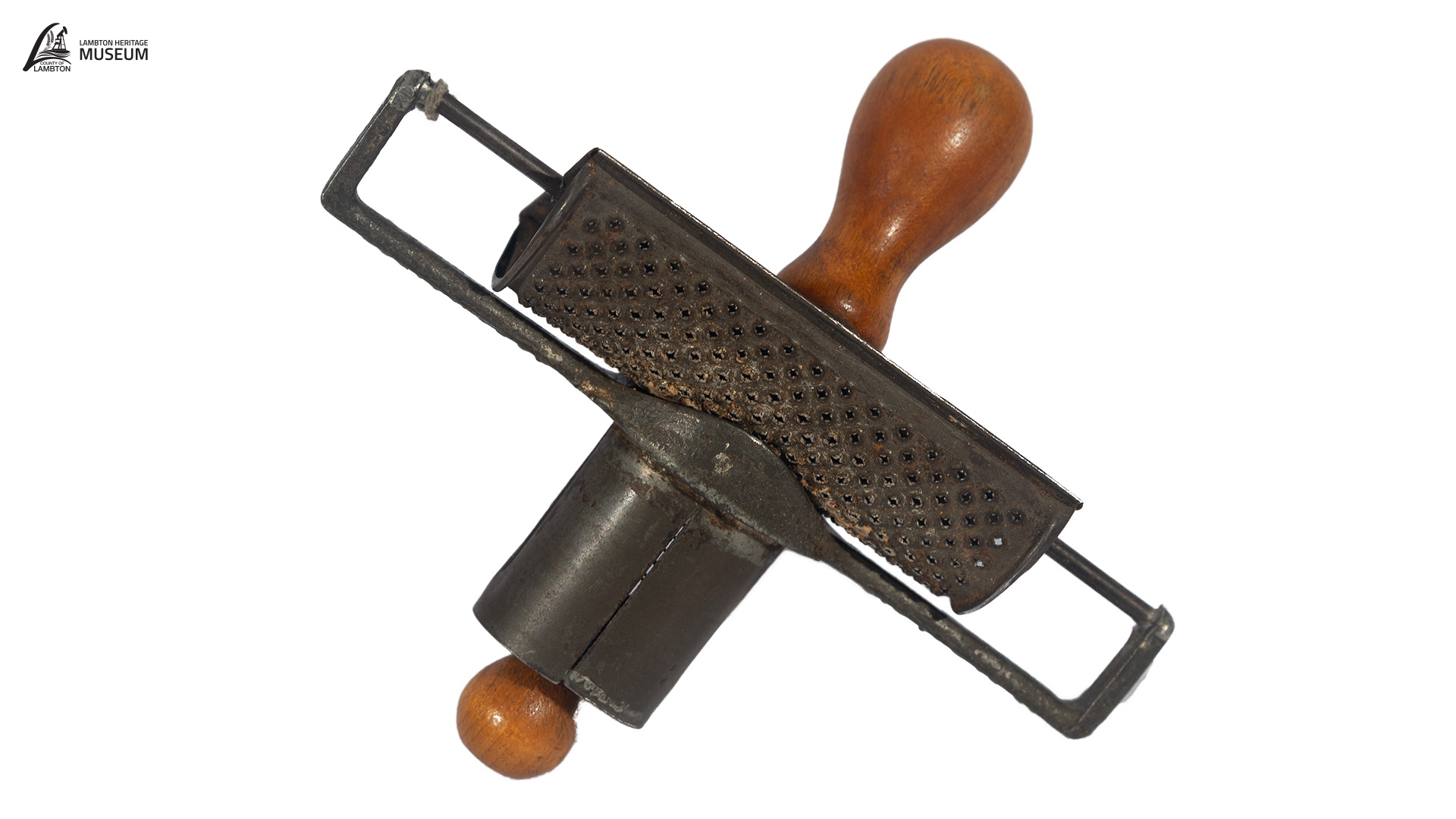 Close-up of an antique metal kitchen tool with a perforated surface and wooden handles, photographed against a white background