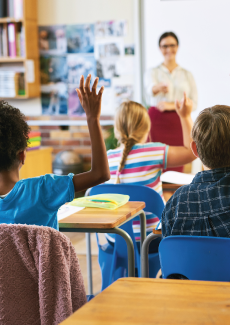 Shot of an unrecognizable group of children sitting in their school classroom and raising their hands to answer a question