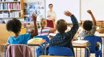 Shot of an unrecognizable group of children sitting in their school classroom and raising their hands to answer a question