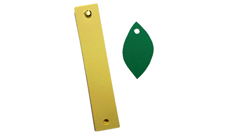 A yellow strip of paper and green paper leaf with a hole.