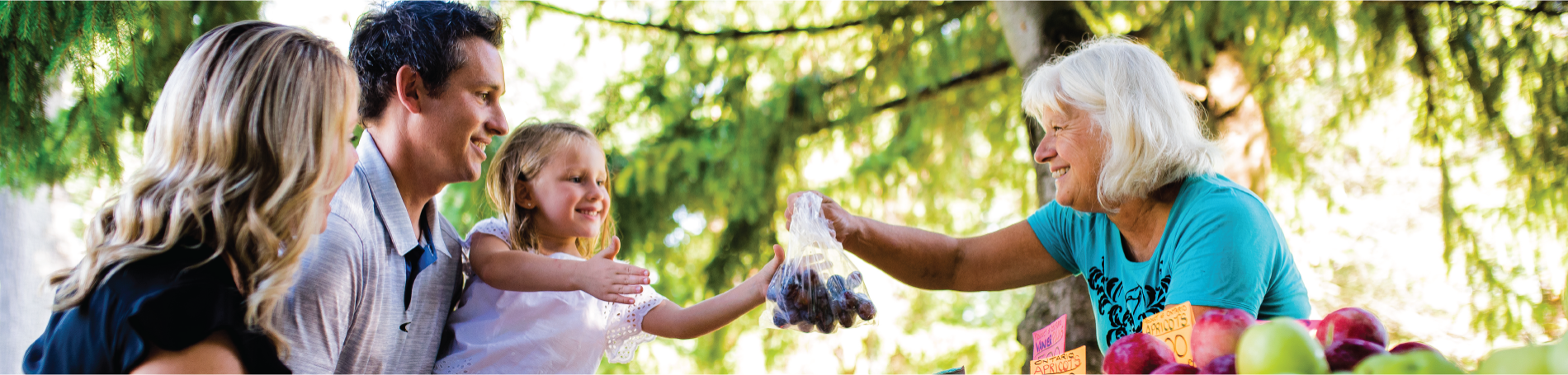 Lady handing family fruit at market.