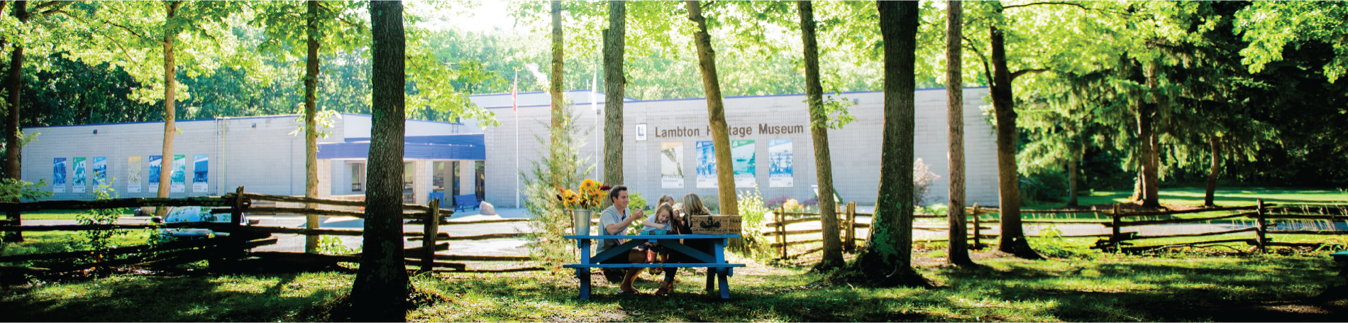 Family sitting on picnic table in front of museum.