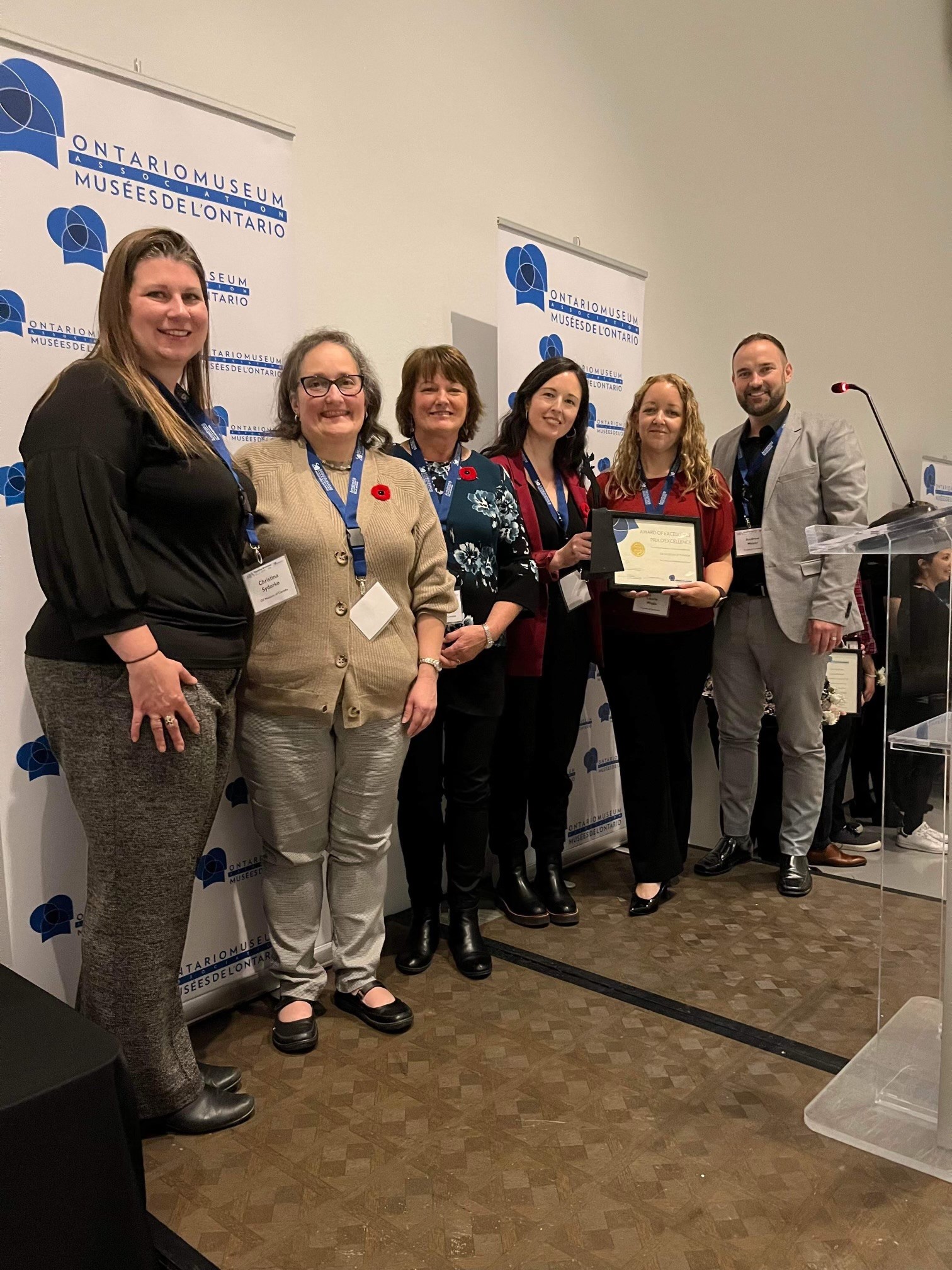 Staff from the Oil Museum of Canada stand in front of an Ontario Museum Association banner accepting an award.