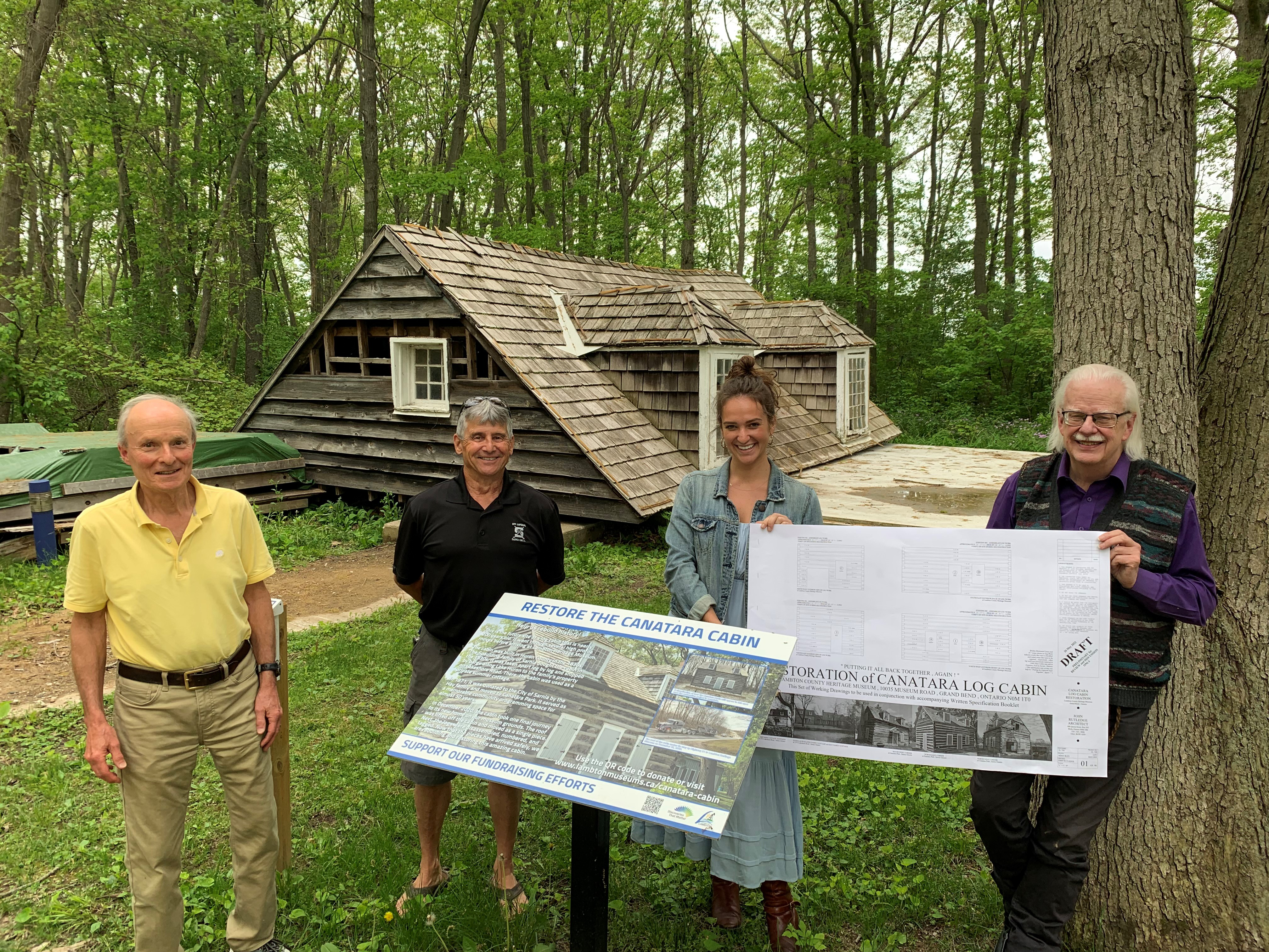 Four people standing in front of a building roof on a ground.