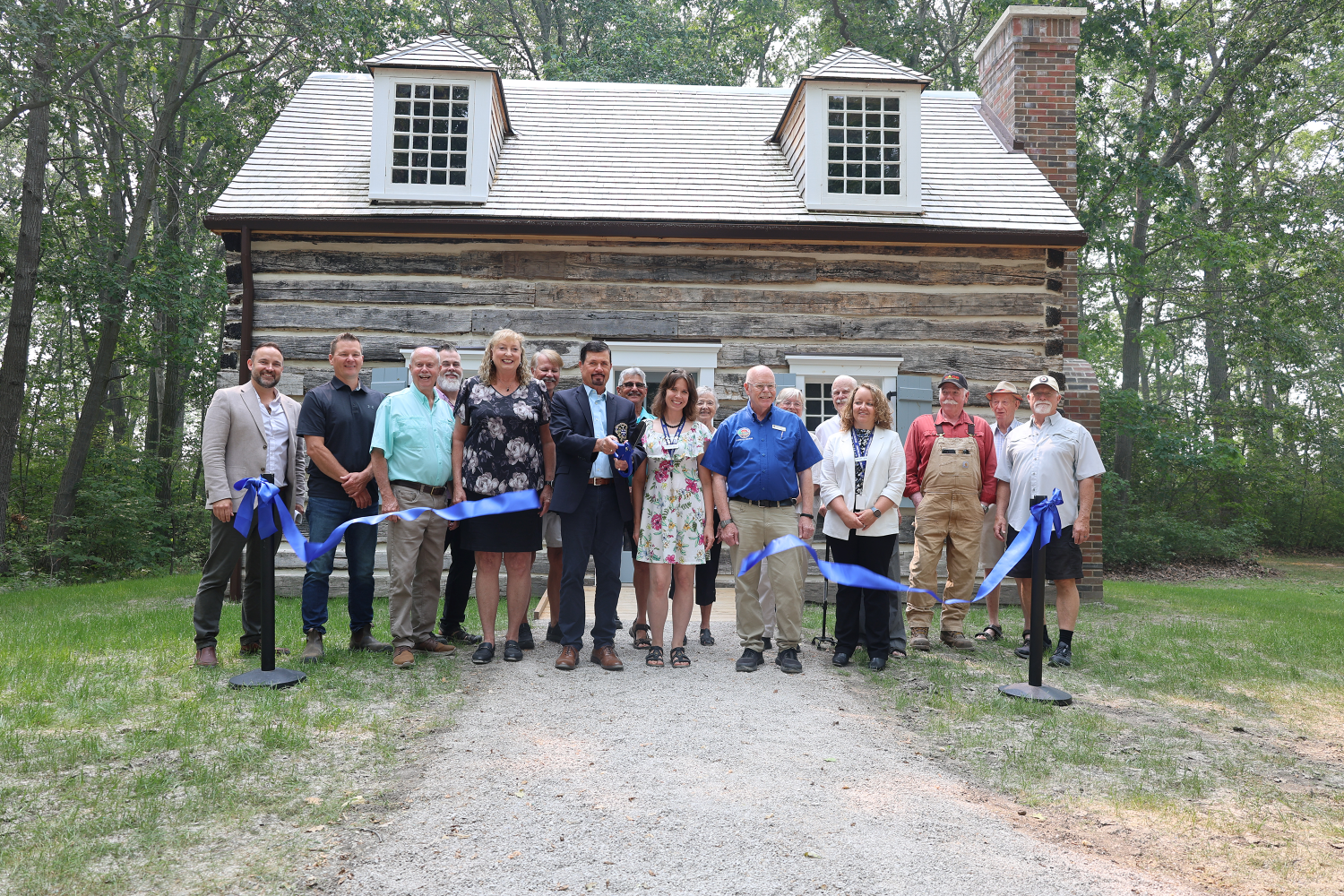 Warden Kevin Marriott officially cuts the ribbon on the restored Canatara Cabin alongside MP Marilyn Gladu, Lambton Heritage Museum Curator/Supervisor Dana Thorne, Lambton Shores Mayor Doug Cook, and the many community members, tradespeople, donors, and supporters whose dedication and generosity made this six-year restoration project possible.