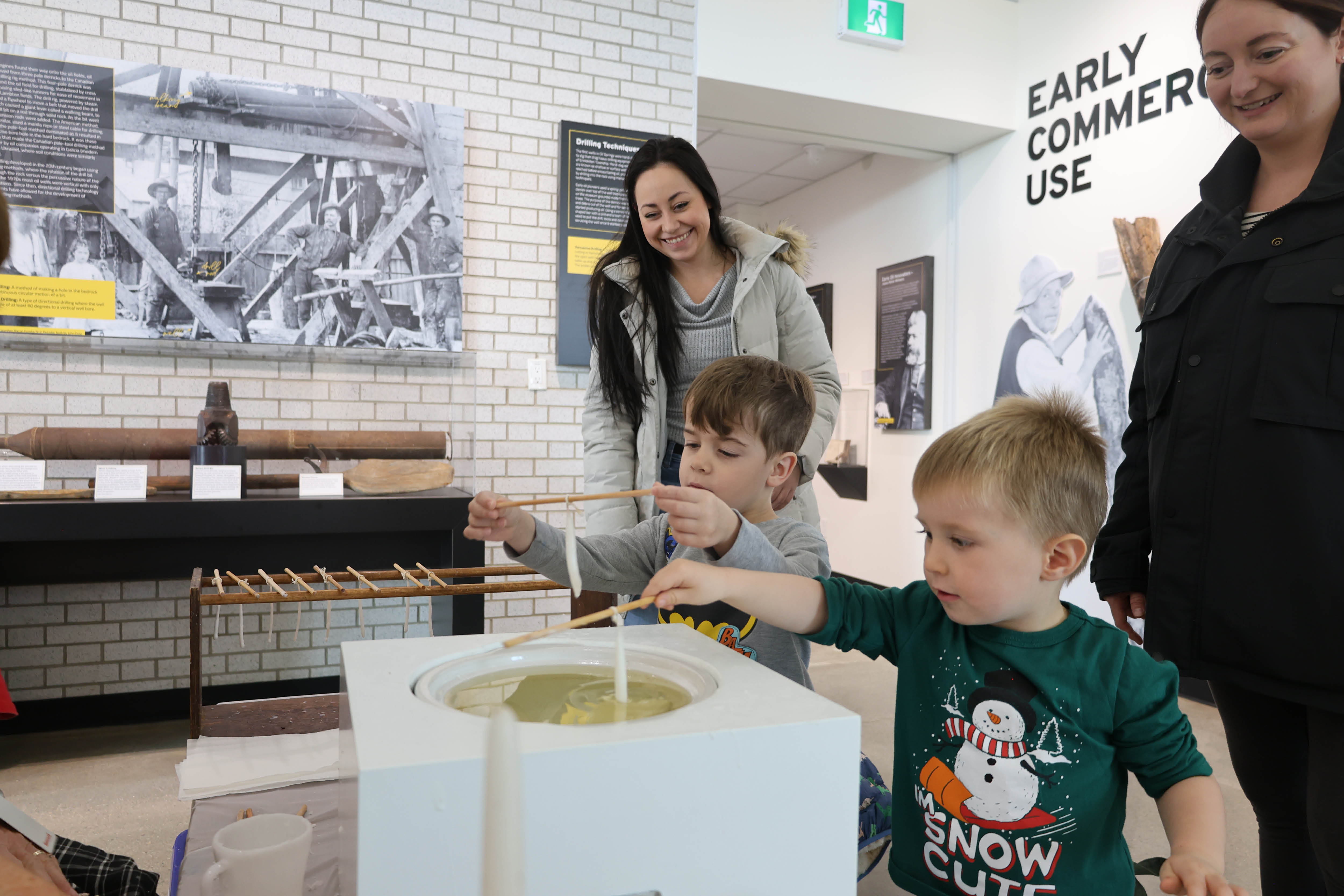 Children practice dipping candles at the Oil Museum of Canada