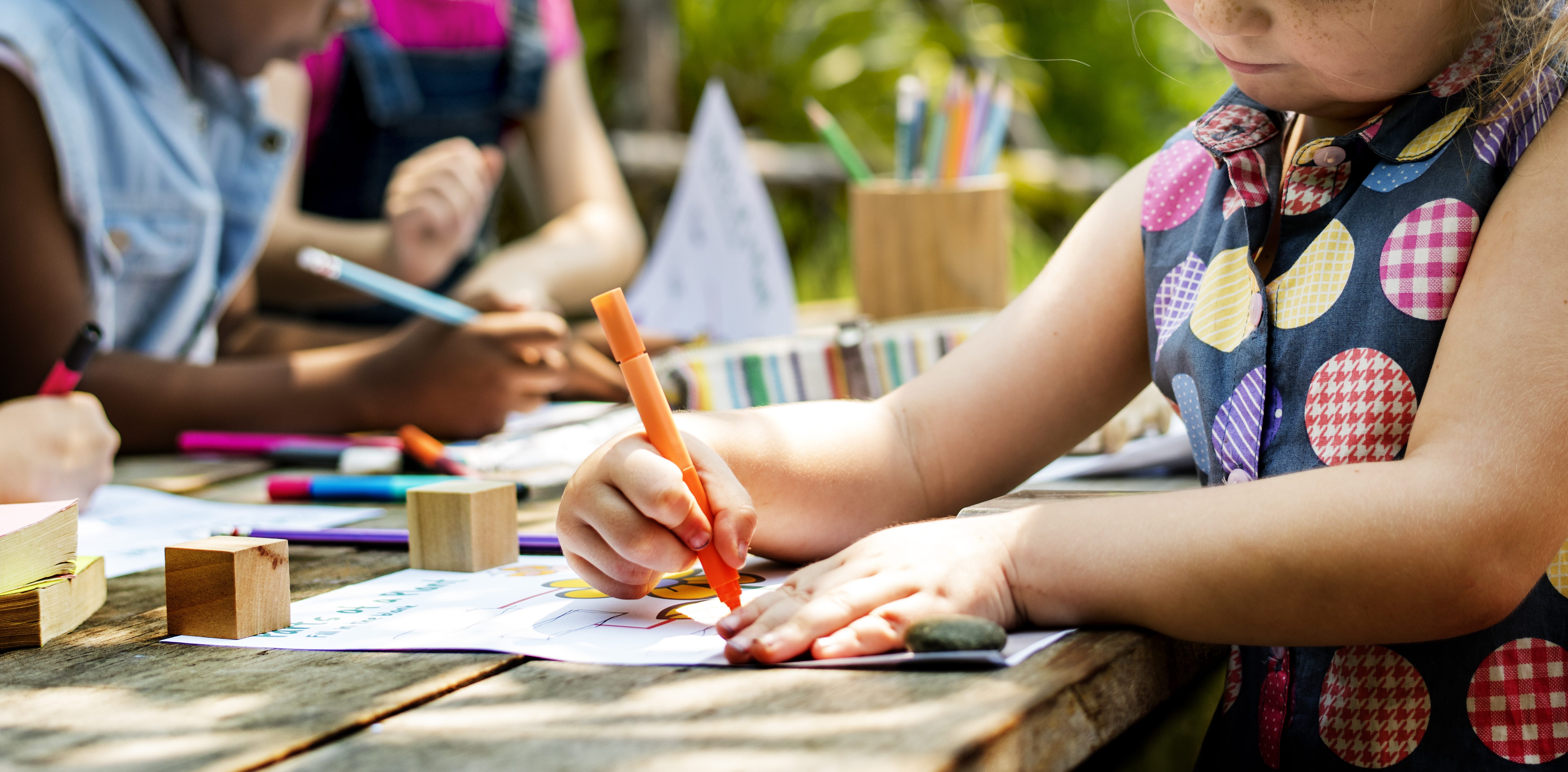 Child colouring outside on picnic table.