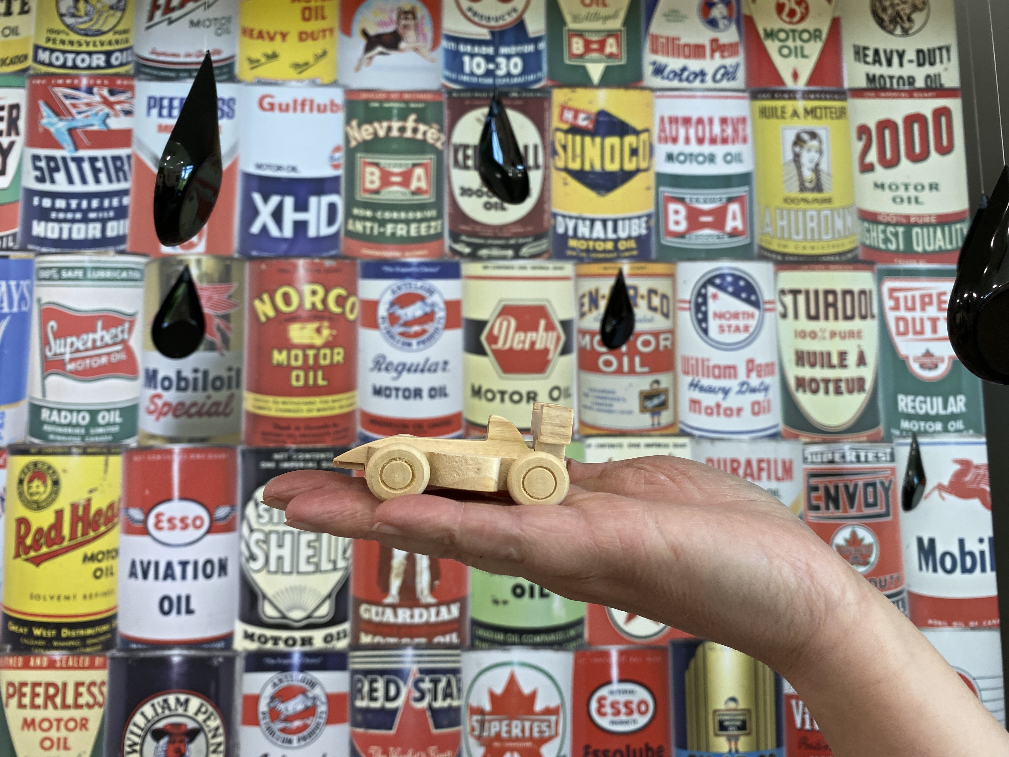 A toy car in front of a mural of oil cans at the Oil Museum of Canada.