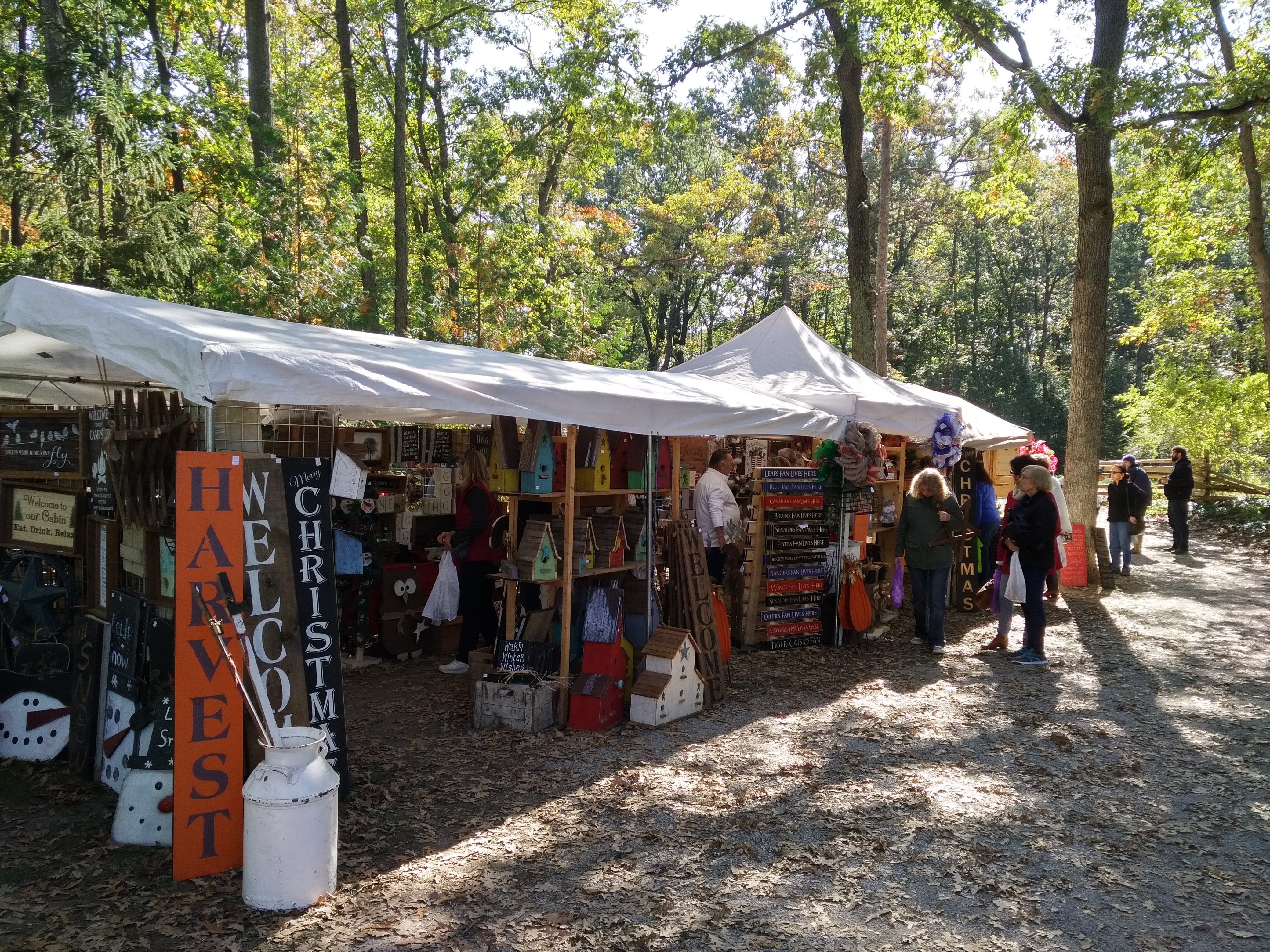 A row of tents selling home decor beneath oak trees at the Lambton Fall Colour & Craft Festival.