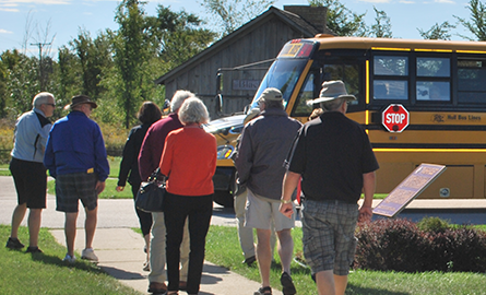 Adults boarding a school bus parked outside of the Museum.