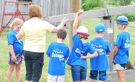 Group of children with volunteer learning about oil derricks.