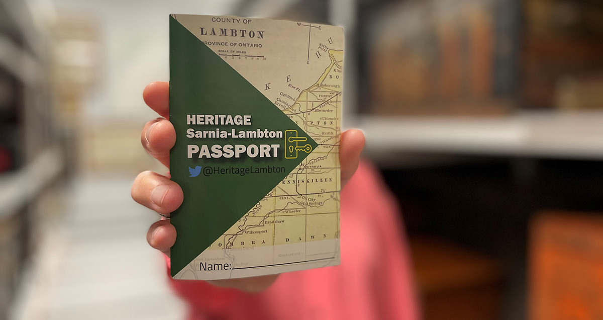 a hand holding out the Heritage Sarnia-Lambton Passport