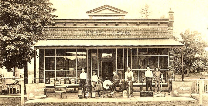 Post card of men outside a business.